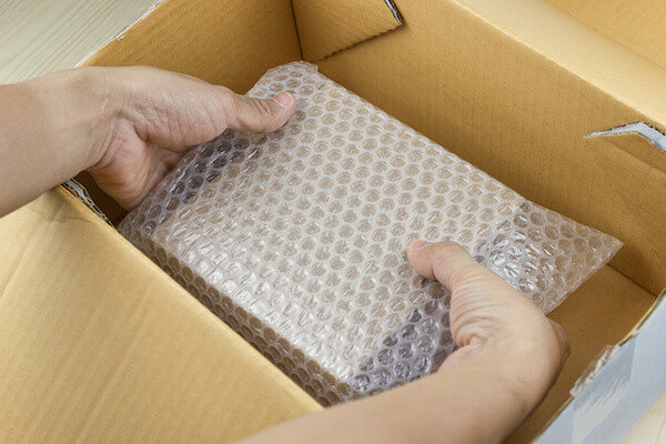 hand of man hold Bubbles covering the box by bubble wrap for protection product