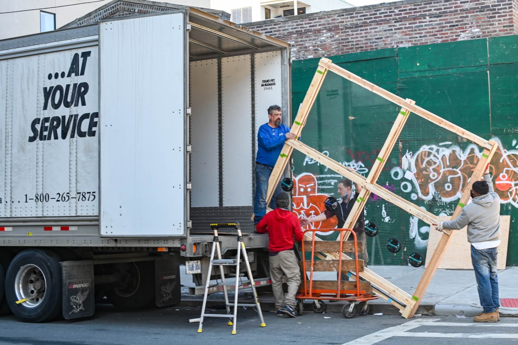 Bed frame being loaded into a moving van by moving professionals